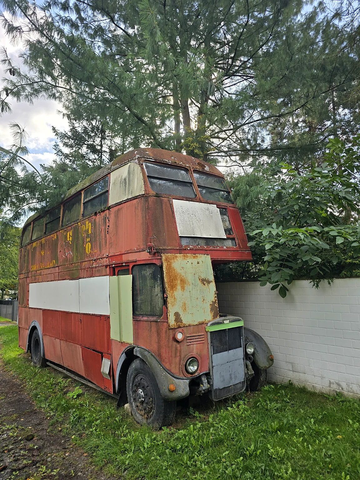 Verwitterter alter Doppeldeckerbus zwischen Bäumen