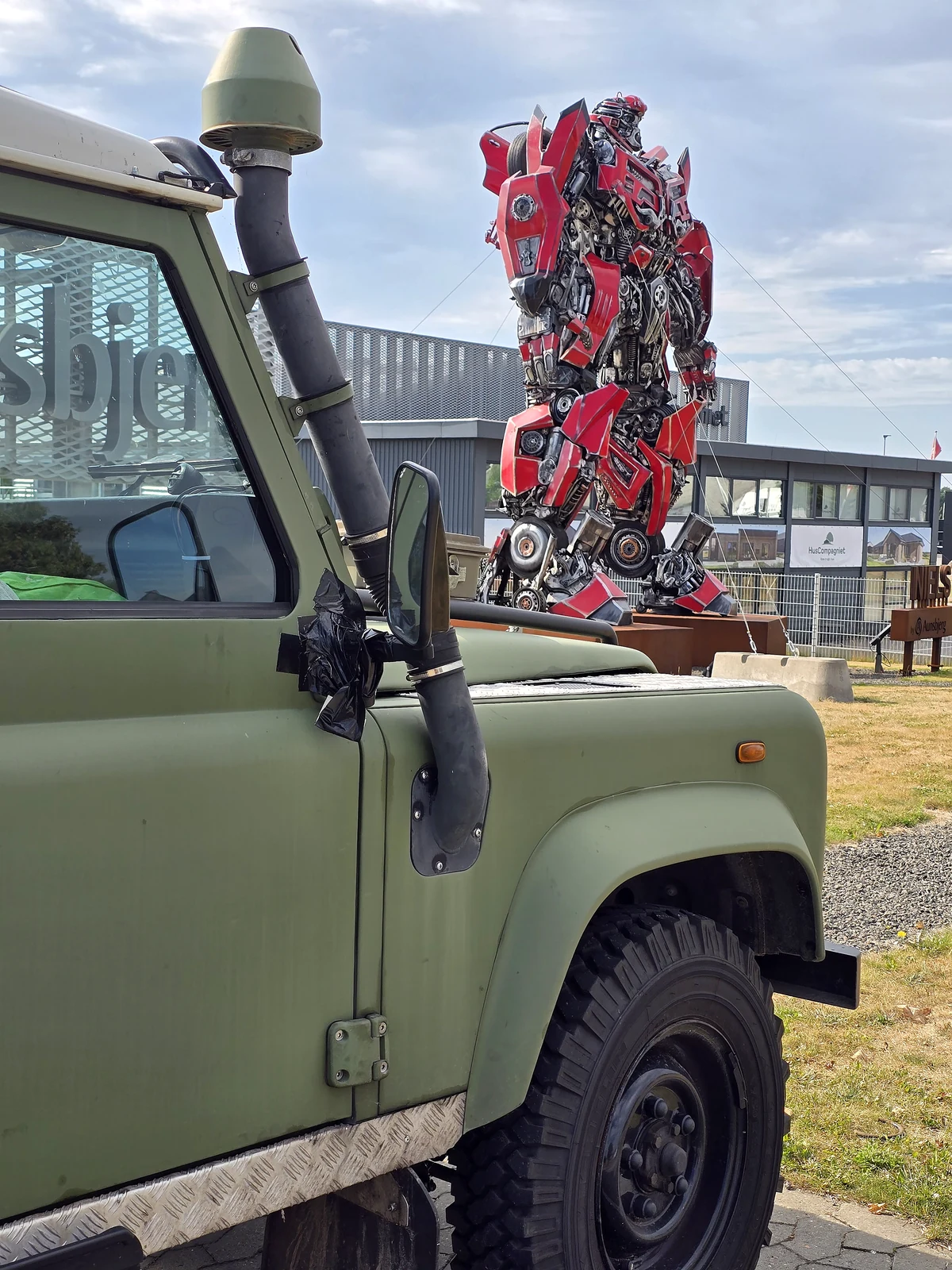 Mein Defender neben einer großen Roboterskulptur auf einem Roadtrip