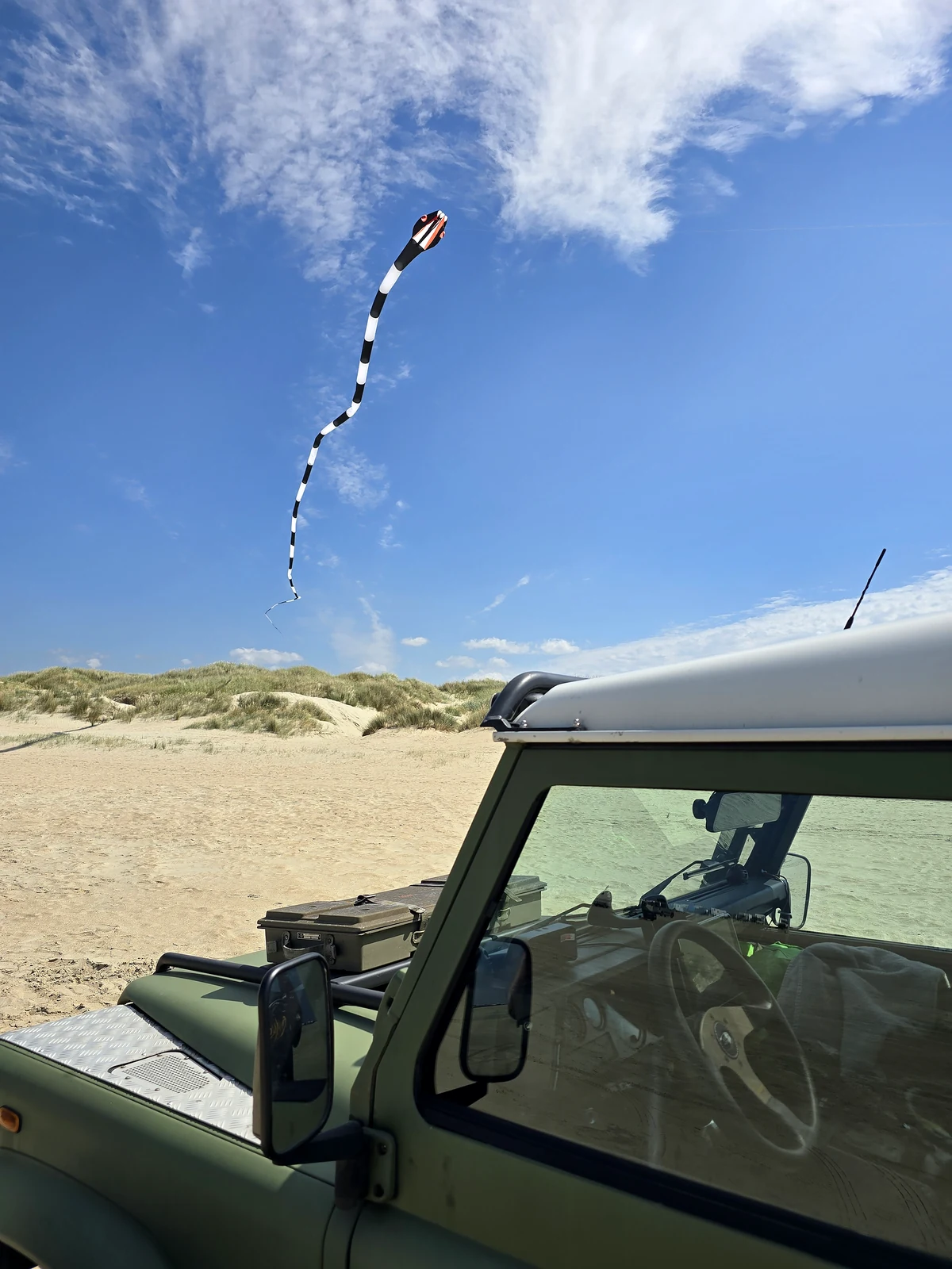 Defender am Strand mit großem Drachen über den Dünen